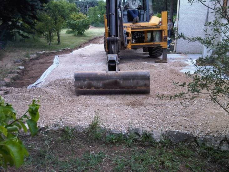 Création d’accès chantier : lit de grave nivelé le long d’une maison