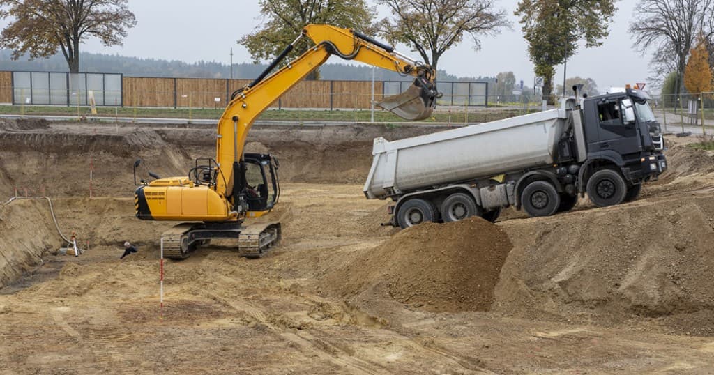 Évacuation des terres : pelle chargeant un camion benne sur chantier